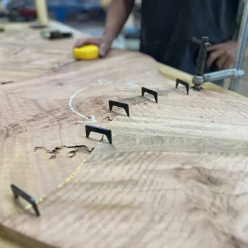 Craftsman fitting two eucalyptus puzzle pieces together with seam clips and glue along the joint