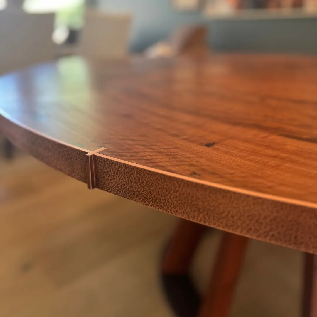 Close-up of the 2-inch hand-hammered copper band where a copper inlay seam meets the table edge Close-up of the 2-inch hand-hammered copper band where a copper inlay seam meets the table edge